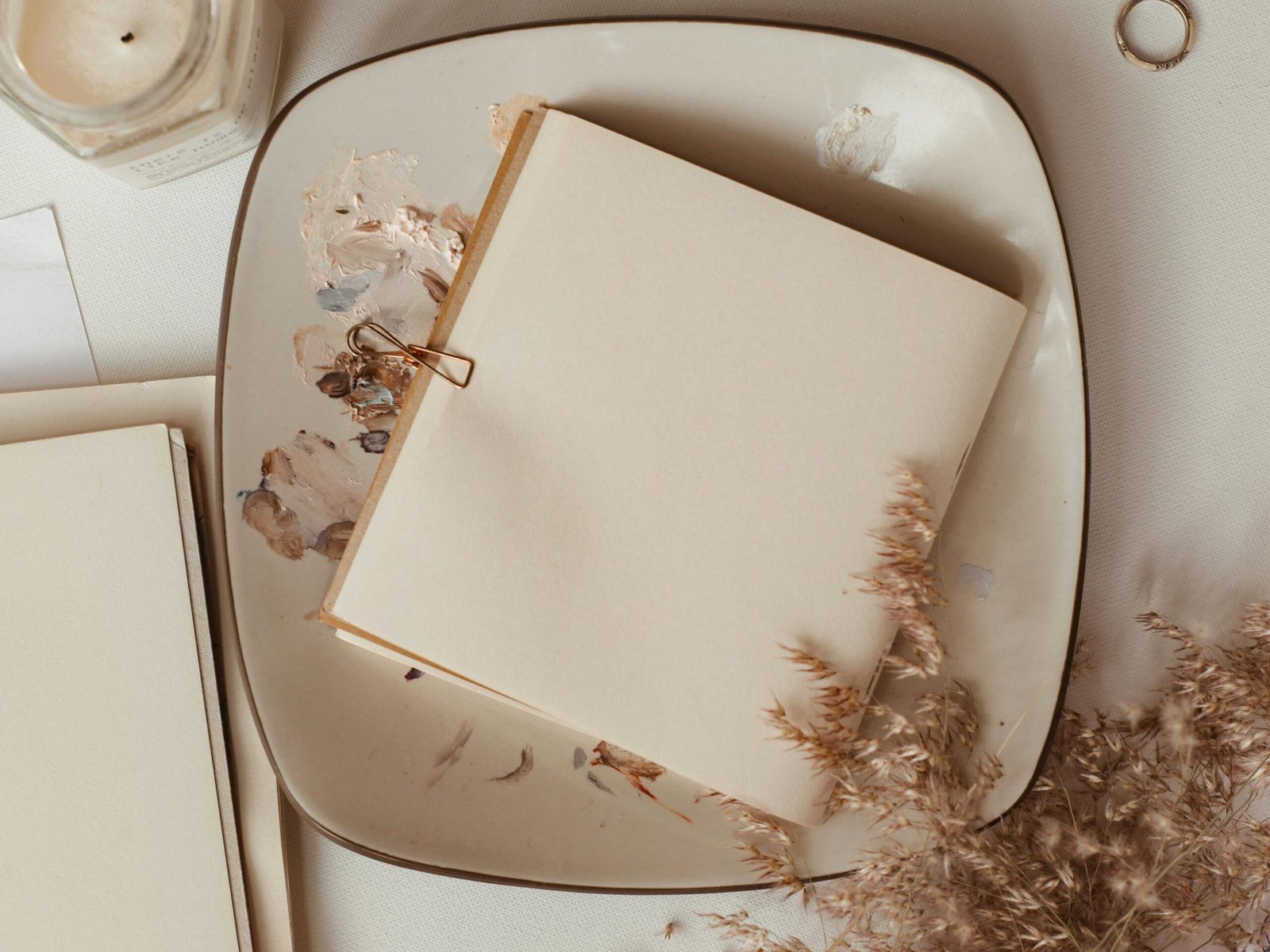 A blank notebook on a painted plate with natural decor, perfect for creative inspiration.